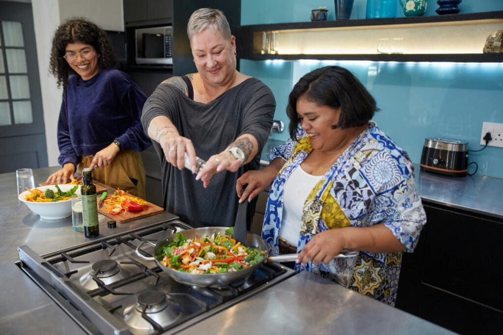 Women smile and laugh together at a cooking class and supper club that is one of the best hobbies for women
