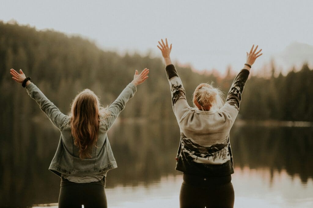 Women raise their hands together overcoming impostor syndrome women